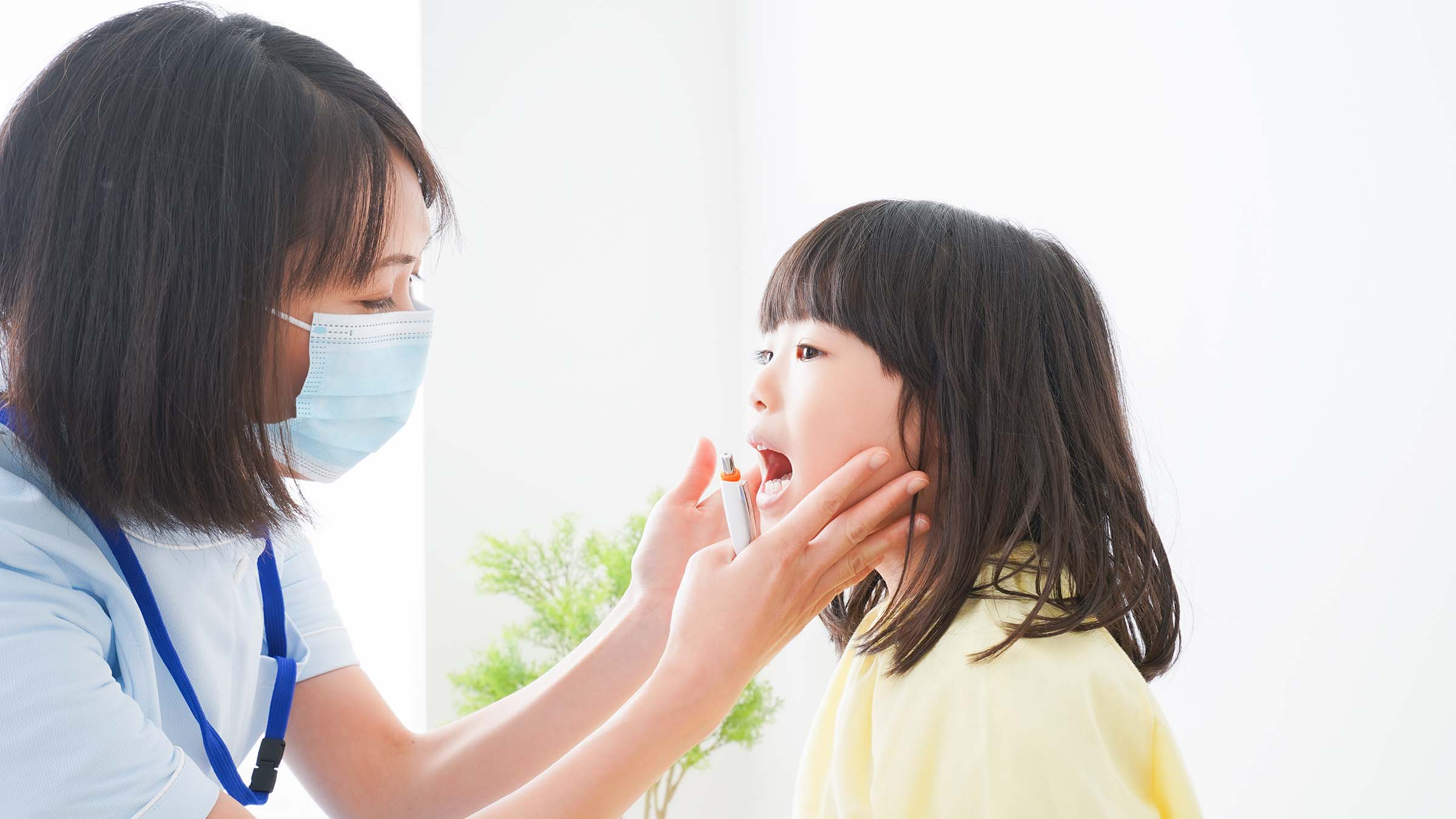 女性歯科医が子供の口腔内を診察している写真